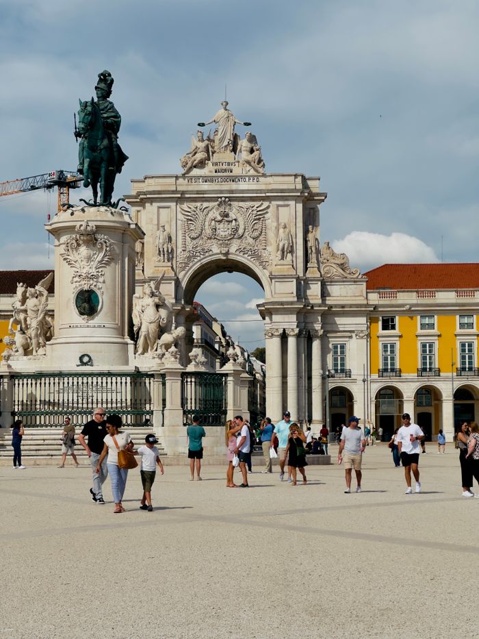 Vibrant scene of tourists at Praça do Comércio with the iconic arch and statue in Lisbon.
