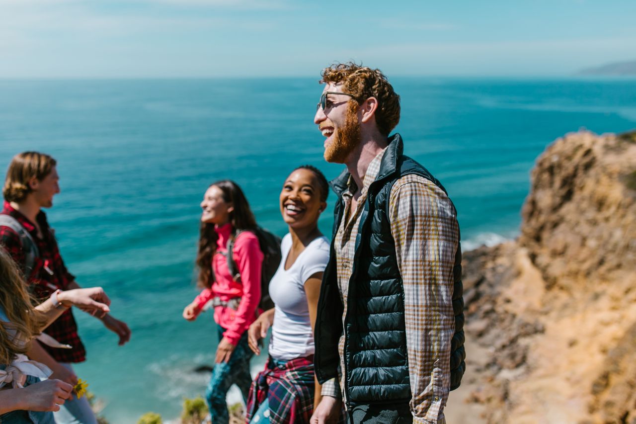 A joyful group of friends hiking along a scenic coastline, enjoying laughter and good company.
