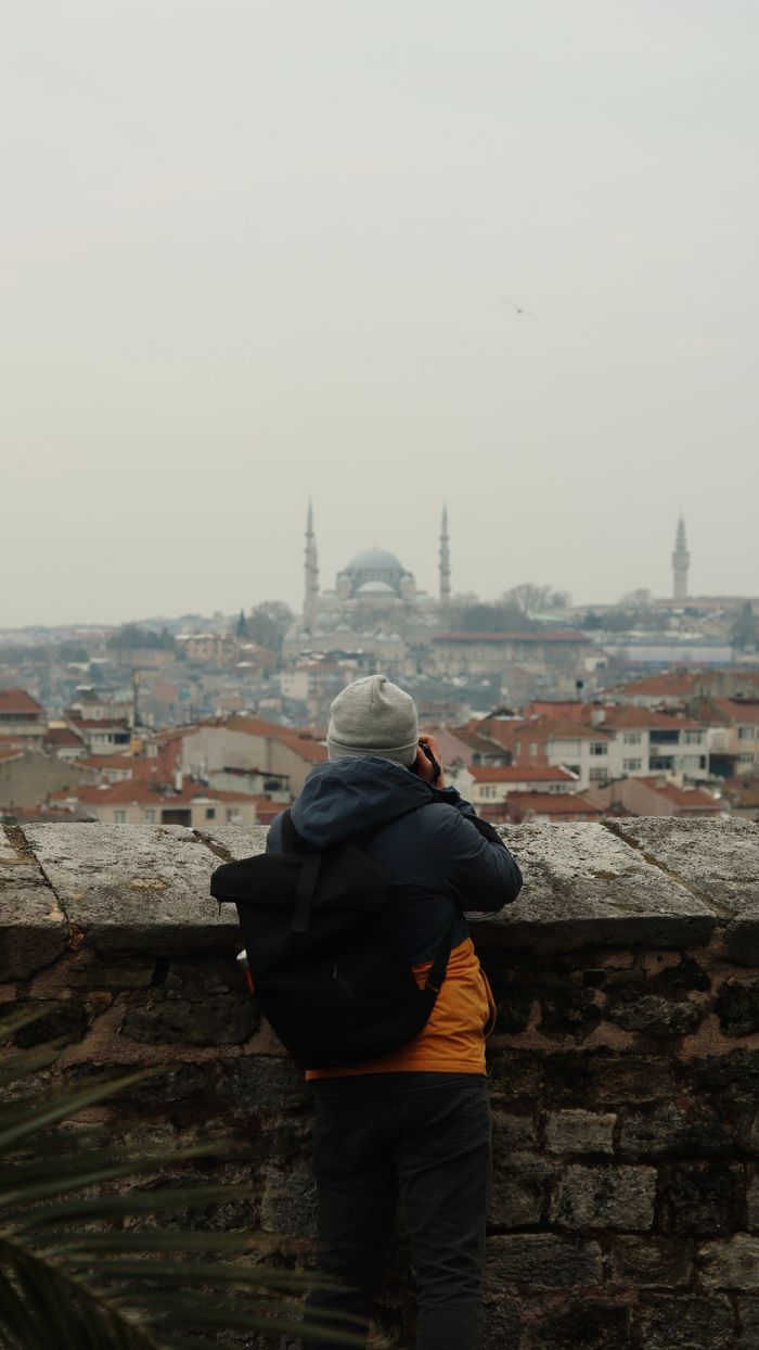 Home A man takes a photo of Istanbul's skyline featuring domes and minarets. Ideal for travel themes.