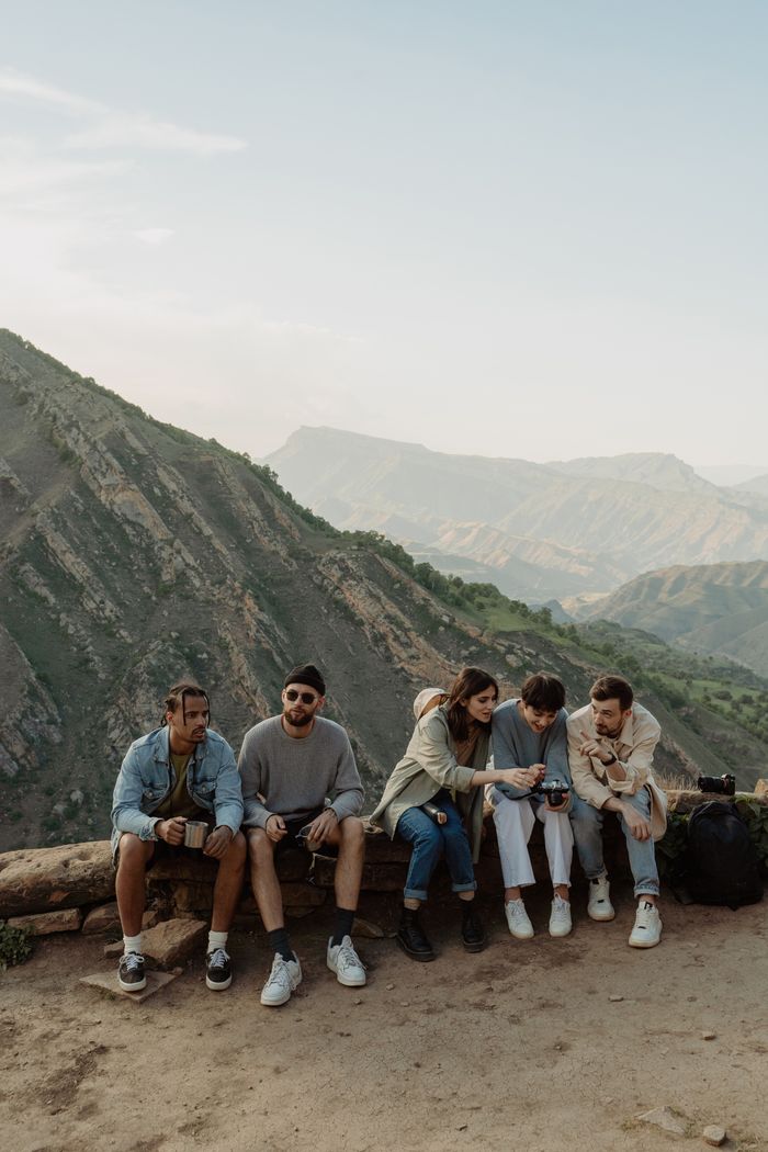 Group of friends relaxing on a mountain edge with a scenic view.